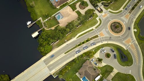 Aerial view of american suburban area with rural road roundabout intersection with moving cars traffic. Circular transportation crossroads in Florida.